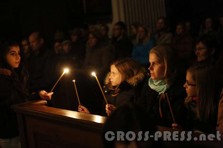 2015.10.31_20.47.59.JPG - Das Licht der Osterkerze wurde in der dunklen Kirche weitergegeben.